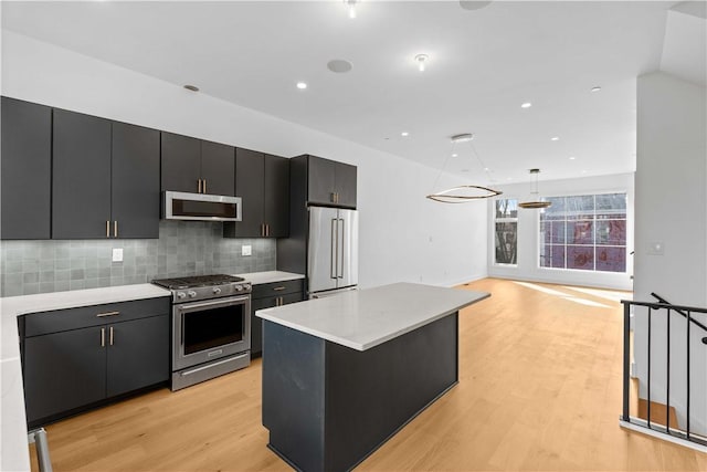 234 44th St, Lawrenceville, PA 15201 - kitchen featuring appliances with stainless steel finishes, dark cabinetry, light countertops, light wood-style floors, and backsplash