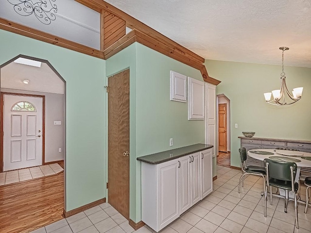 305 Ivy Dr, Pine Twp Nal, PA 15044 - kitchen with lofted ceiling, arched walkways, a chandelier, white cabinets, and dark countertops