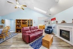 1011 Sunnyfield Ct, Penn Twp Wml, PA 15636 - living area featuring wood finished floors, a ceiling fan, lofted ceiling, a glass covered fireplace, and a skylight