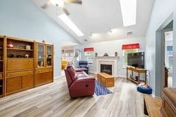 1011 Sunnyfield Ct, Penn Twp Wml, PA 15636 - living room with a skylight, lofted ceiling, ceiling fan, a fireplace, and wood finished floors