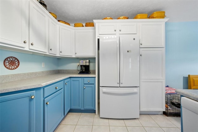 1011 Sunnyfield Ct, Penn Twp Wml, PA 15636 - kitchen with freestanding refrigerator, blue cabinetry, light tile patterned floors, light countertops, and white cabinetry