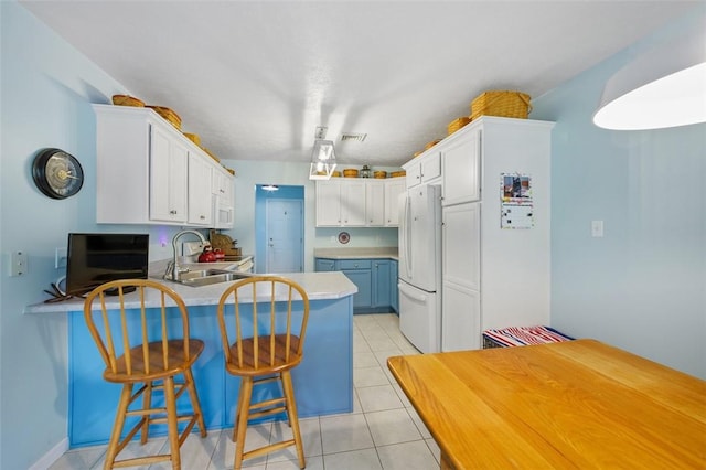 1011 Sunnyfield Ct, Penn Twp Wml, PA 15636 - kitchen featuring freestanding refrigerator, a sink, a peninsula, light tile patterned floors, and a breakfast bar area