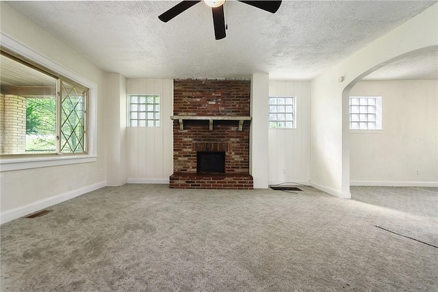 163 Universal Rd, Penn Hills, PA 15235 - unfurnished living room featuring plenty of natural light, a textured ceiling, a ceiling fan, a brick fireplace, and carpet flooring