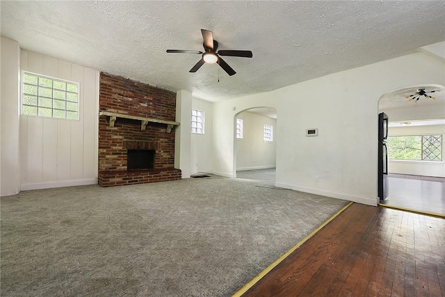 163 Universal Rd, Penn Hills, PA 15235 - unfurnished living room featuring arched walkways, a ceiling fan, a textured ceiling, and a brick fireplace