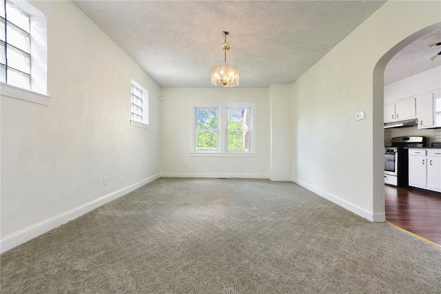 163 Universal Rd, Penn Hills, PA 15235 - empty room with a textured ceiling, a chandelier, arched walkways, baseboards, and dark colored carpet