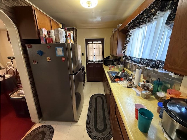 7134 Gladefield St, Lincoln-Larimer, PA 15206 - kitchen featuring freestanding refrigerator, a sink, light tile patterned flooring, light countertops, and arched walkways