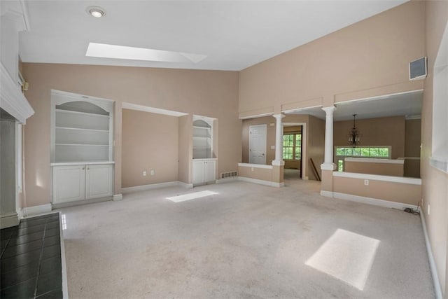 10276 Rinaman Rd, Mccandless, PA 15090 - unfurnished living room featuring carpet flooring, a skylight, baseboards, high vaulted ceiling, and ornate columns