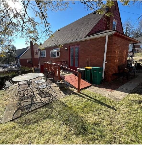 5 Barton Dr, Churchill Boro, PA 15221 - rear view of property featuring french doors, roof with shingles, brick siding, a deck, and a yard