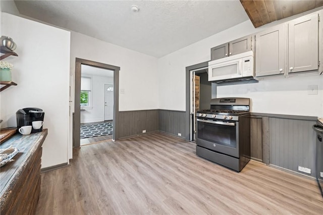 507 Sells Ln, Hempfield Twp Wml, PA 15601 - kitchen with stainless steel gas range, white microwave, wainscoting, light wood finished floors, and light countertops