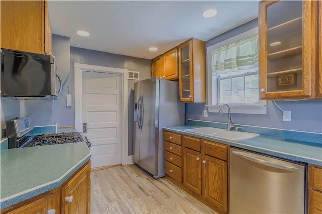 136 E Crafton Ave, Crafton, PA 15205 - kitchen featuring appliances with stainless steel finishes, a sink, brown cabinets, light wood finished floors, and glass insert cabinets