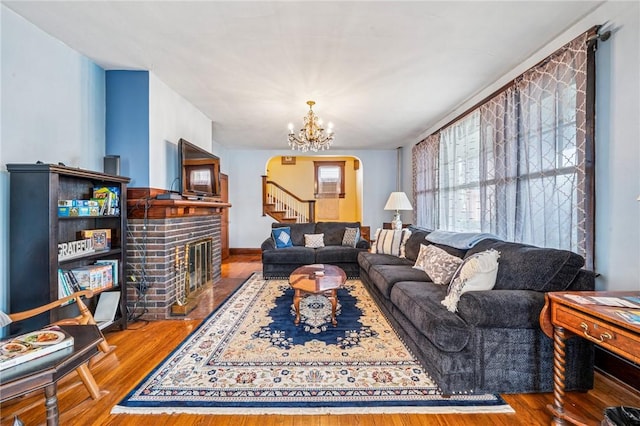 301 W Patriot St, Somerset Boro, PA 15501 - living room with arched walkways, a brick fireplace, a chandelier, wood finished floors, and stairs