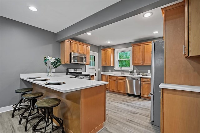273 Inglewood Dr, Mt Lebanon, PA 15228 - kitchen featuring stainless steel appliances, a peninsula, light wood-style floors, a sink, and a kitchen breakfast bar