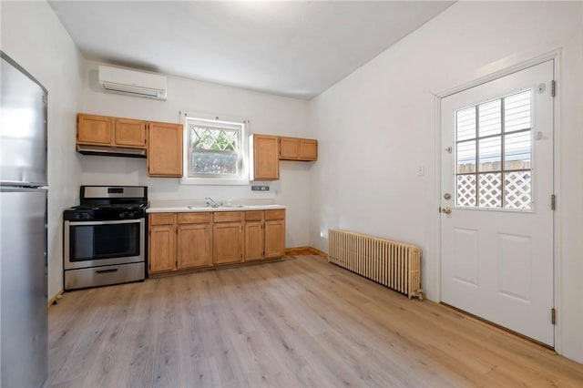 636 Edmond St, Bloomfield, PA 15224 - kitchen with radiator, stainless steel appliances, a wall unit AC, light wood-style floors, and under cabinet range hood