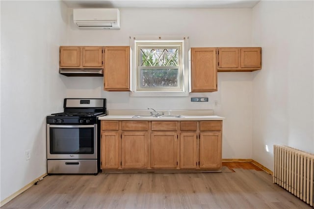 636 Edmond St, Bloomfield, PA 15224 - kitchen featuring radiator heating unit, stainless steel range with gas cooktop, a wall mounted air conditioner, a sink, and light wood-type flooring