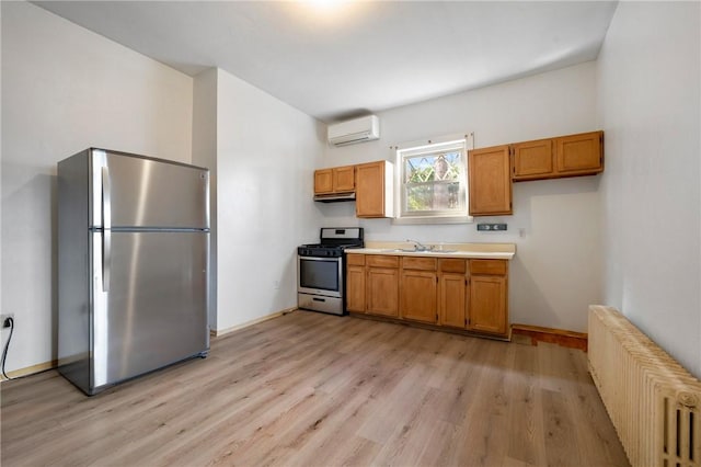 636 Edmond St, Bloomfield, PA 15224 - kitchen with stainless steel appliances, radiator heating unit, a wall unit AC, light countertops, and light wood finished floors