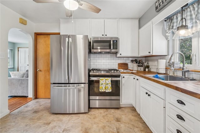 1507 Woodlawn Dr, Unity Twp, PA 15650 - kitchen featuring appliances with stainless steel finishes, a sink, wooden counters, arched walkways, and ceiling fan