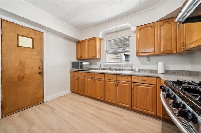 7333 Mcclure Ave, Swissvale, PA 15218 - kitchen with stainless steel appliances, a sink, ornamental molding, brown cabinetry, and light wood-style flooring