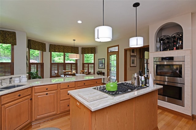 3875 Ashland Ct, Hampton, PA 15101 - kitchen with appliances with stainless steel finishes, a sink, light wood finished floors, a kitchen island, and a tile fireplace