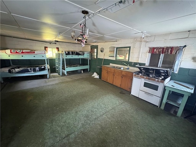23682 Rte 949, Ridgway, PA 15853 - kitchen with white gas stove, concrete block wall, a sink, and concrete floors