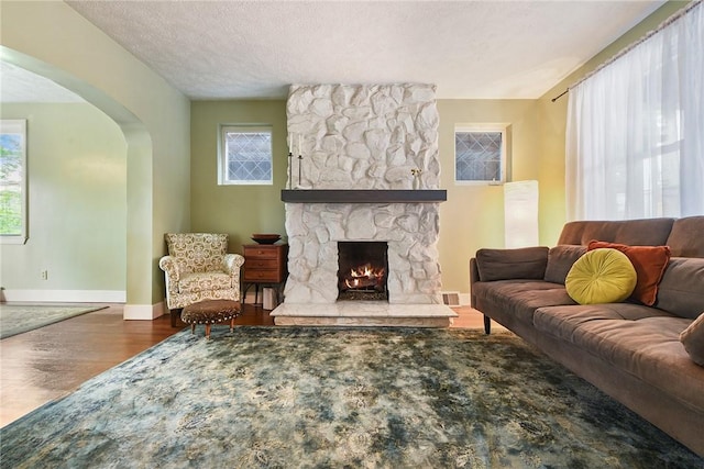 1521 Claim St, Troy Hill, PA 15212 - living room with arched walkways, wood finished floors, a stone fireplace, baseboards, and a textured ceiling
