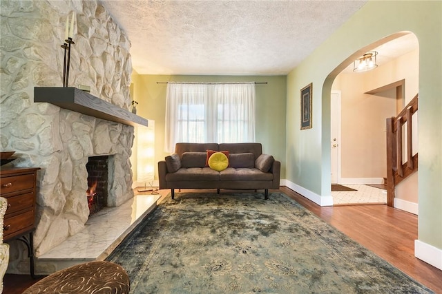 1521 Claim St, Troy Hill, PA 15212 - living room with arched walkways, wood finished floors, a textured ceiling, baseboards, and a fireplace