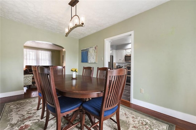 1521 Claim St, Troy Hill, PA 15212 - dining room with arched walkways, baseboards, wood finished floors, and a textured ceiling