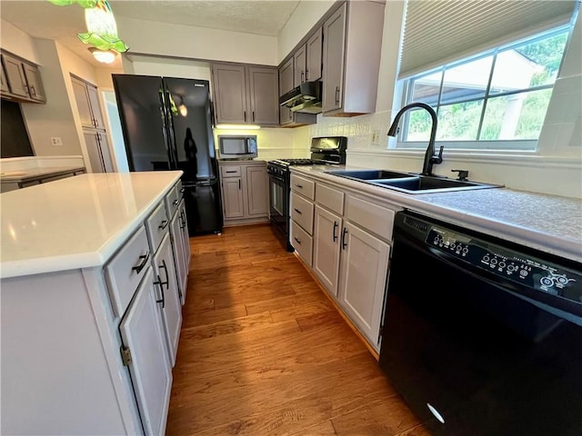 758 Venango Ave, Shaler, PA 15209 - kitchen with black appliances, a sink, under cabinet range hood, light countertops, and light wood-style flooring