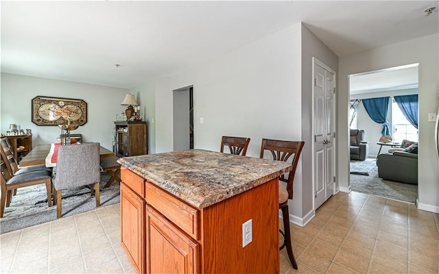 411 Fairgate, Pine Twp, PA 15090 - kitchen with a center island, a breakfast bar area, brown cabinets, and light tile patterned flooring