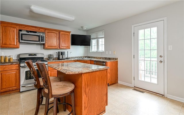 411 Fairgate, Pine Twp, PA 15090 - kitchen with appliances with stainless steel finishes, a kitchen island, brown cabinetry, and a kitchen breakfast bar
