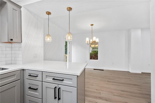 36 W Bellecrest, Brentwood, PA 15227 - kitchen with gray cabinetry, light wood-style floors, a peninsula, tasteful backsplash, and lofted ceiling