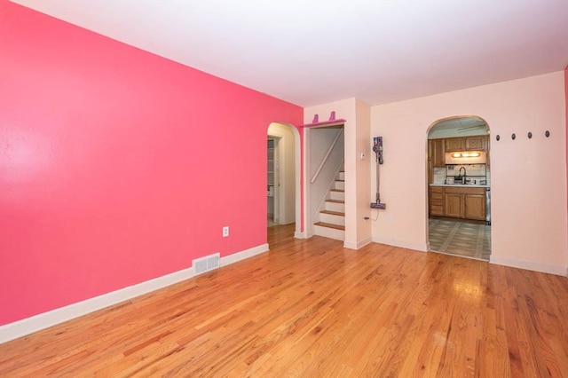 117 Derby Way, Aliquippa, PA 15001 - empty room featuring arched walkways, light wood finished floors, baseboards, stairs, and a sink