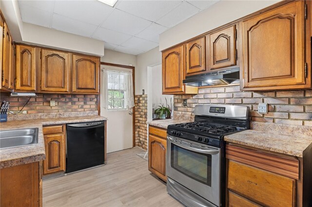 545 Ohio Ave, Midland Boro, PA 15059 - kitchen with stainless steel gas range oven, black dishwasher, under cabinet range hood, brown cabinets, and decorative backsplash