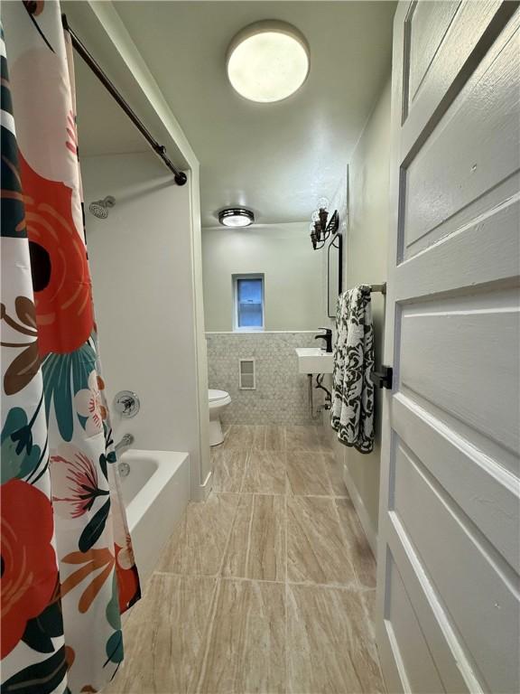 715 Chislett, East Liberty, PA 15206 - bathroom featuring toilet, tile walls, shower / tub combo, wainscoting, and tile patterned flooring