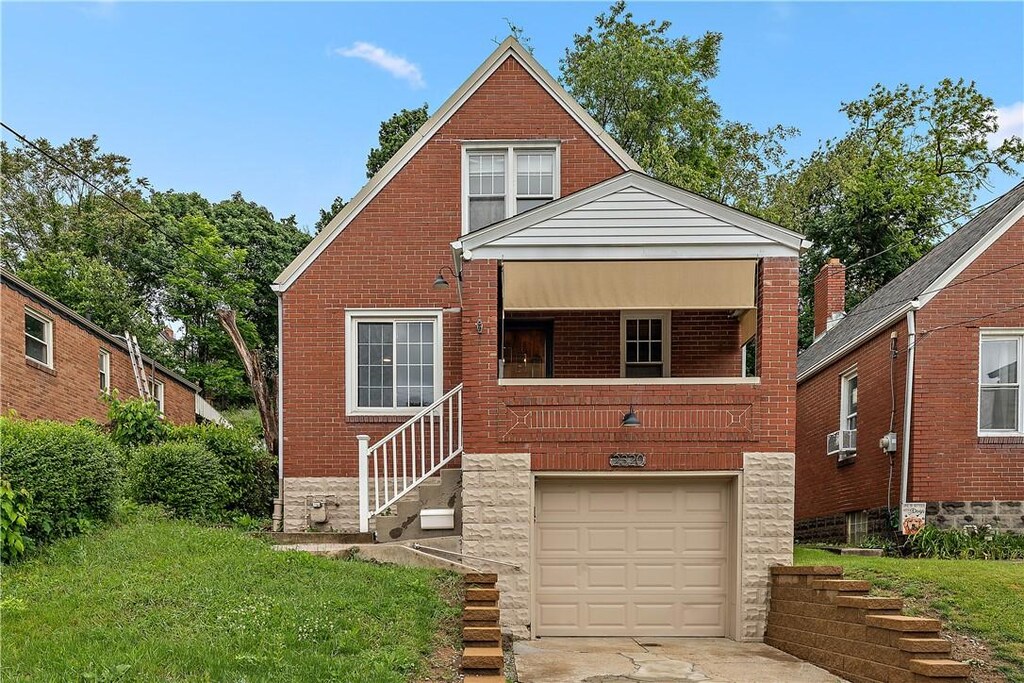 2320 Wolford St, Brookline, PA 15226 - bungalow-style home with an attached garage, brick siding, driveway, stairs, and a front lawn