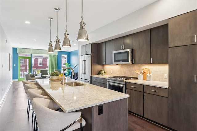 4707 Hatfield St, Lawrenceville, PA 15201 - kitchen featuring stainless steel appliances, a kitchen bar, tasteful backsplash, dark brown cabinetry, and an island with sink