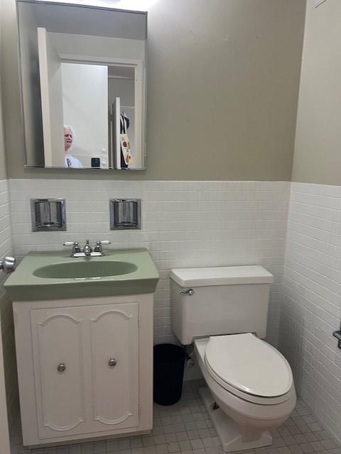 320 Fort Duquesne Blvd Unit 18F, Downtown Pgh, PA 15222 - bathroom featuring vanity, toilet, tile walls, a wainscoted wall, and tile patterned flooring