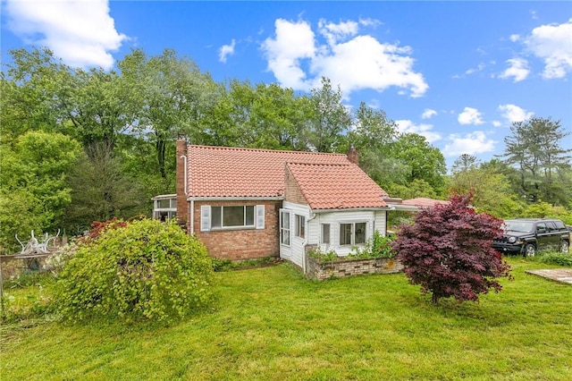 29564 Lake Creek Rd, Pa, PA 16314 - rear view of house featuring a chimney, a tile roof, a yard, and brick siding