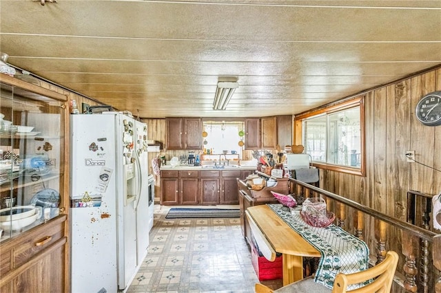 29564 Lake Creek Rd, Pa, PA 16314 - kitchen featuring white refrigerator with ice dispenser, light floors, wood walls, brown cabinetry, and a sink