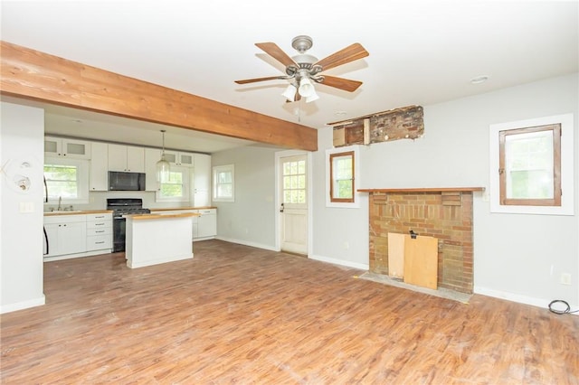 1017 Olive Ave, Natrona Hts/Harrison Twp, PA 15065 - unfurnished living room featuring a brick fireplace, light wood finished floors, a ceiling fan, and baseboards