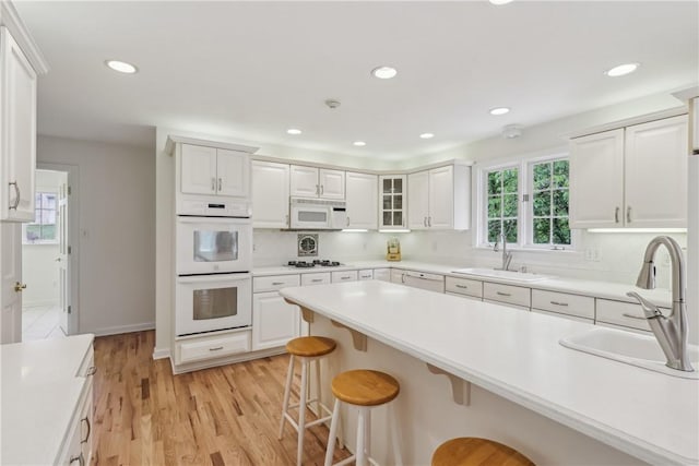 131 Hidden Valley Rd, Murrysville, PA 15146 - kitchen featuring a sink, white appliances, a breakfast bar, white cabinetry, and recessed lighting