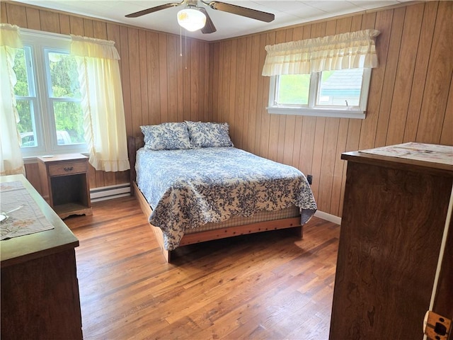 1126 Slate Point Rd, Parks Twp, PA 15690 - bedroom featuring baseboard heating, wooden walls, light wood-style flooring, and a ceiling fan