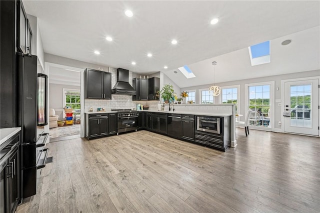 8426 David Dr, South Fayette, PA 15017 - kitchen with wall chimney range hood, high end range, a skylight, dark cabinets, and light countertops