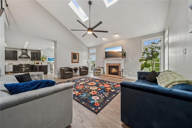 8426 David Dr, South Fayette, PA 15017 - living room featuring a fireplace, high vaulted ceiling, light wood-type flooring, a skylight, and a ceiling fan
