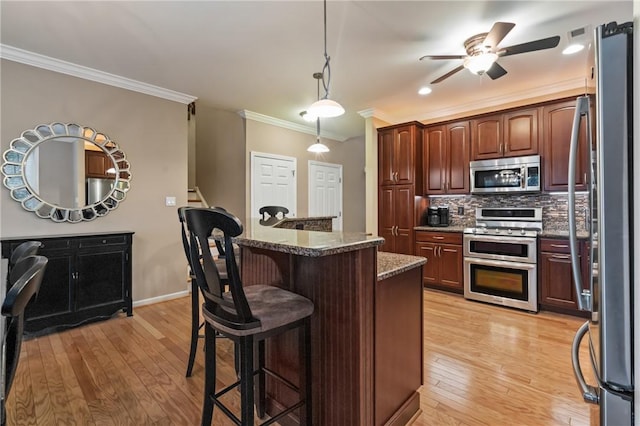 230 Patriot Ln, Economy, PA 15042 - kitchen featuring appliances with stainless steel finishes, ornamental molding, a ceiling fan, a breakfast bar area, and light wood-type flooring
