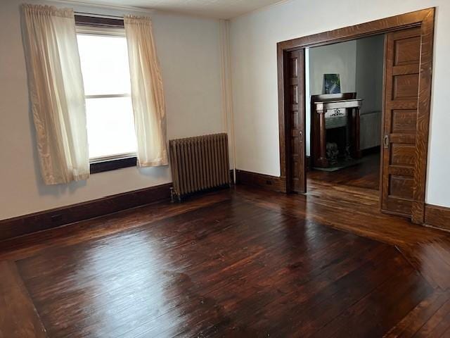 201 Thompson St, Latrobe, PA 15650 - empty room with radiator heating unit, wood-type flooring, a fireplace, and baseboards
