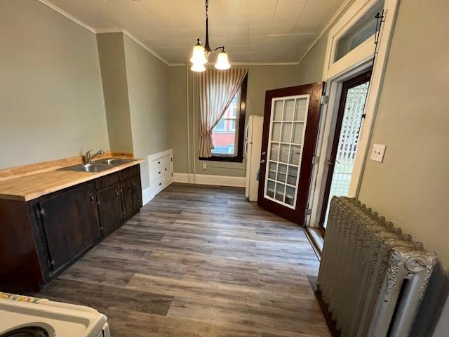 201 Thompson St, Latrobe, PA 15650 - unfurnished dining area with crown molding, dark wood-type flooring, a chandelier, and a sink