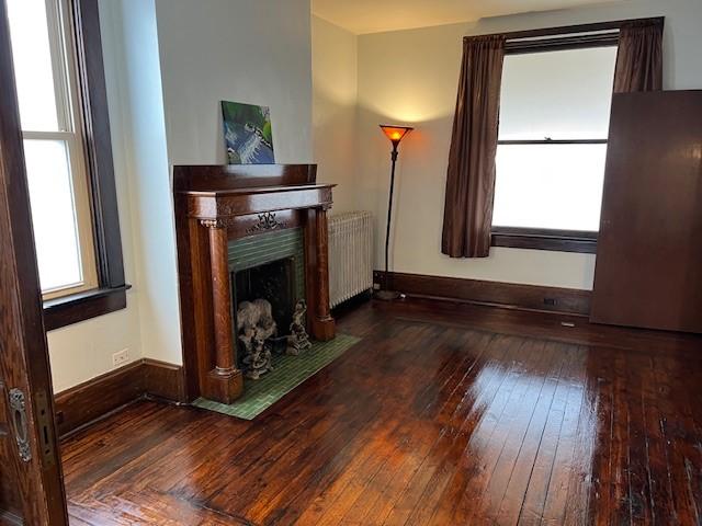 201 Thompson St, Latrobe, PA 15650 - living room featuring radiator, a fireplace with flush hearth, wood-type flooring, and baseboards