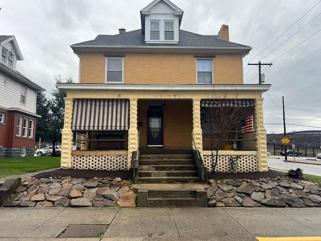 201 Thompson St, Latrobe, PA 15650 - american foursquare style home featuring a porch, brick siding, and a chimney