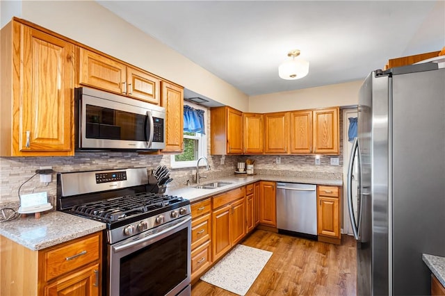 2400 James St, Hopewell Twp Bea, PA 15001 - kitchen with appliances with stainless steel finishes, light wood-style flooring, a sink, decorative backsplash, and light stone countertops