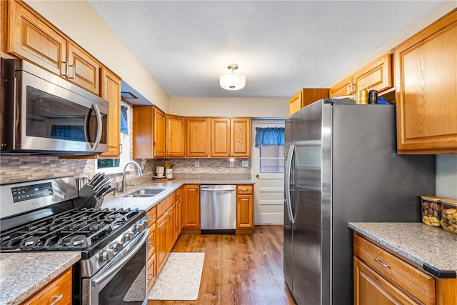 2400 James St, Hopewell Twp Bea, PA 15001 - kitchen featuring appliances with stainless steel finishes, a sink, light wood-style flooring, tasteful backsplash, and brown cabinets